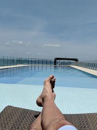 Low section of man in swimming pool against sky