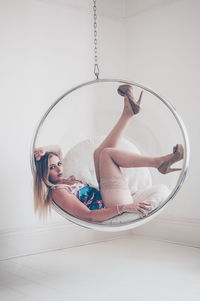 Portrait of woman sitting on white wall