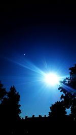 Low angle view of silhouette trees against blue sky