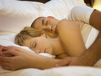 High angle view of couple sleeping on bed at home