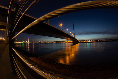 Illuminated bridge over river against sky at night