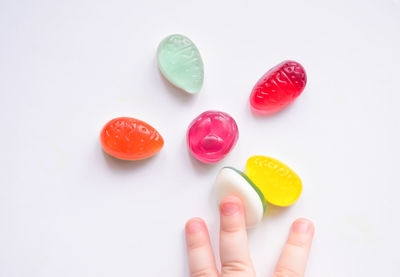 Close-up of hand holding strawberry over white background