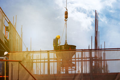 Low angle view of manual worker working at construction site against sky