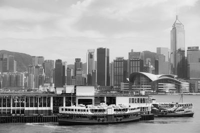 Boats in river by buildings against sky in city