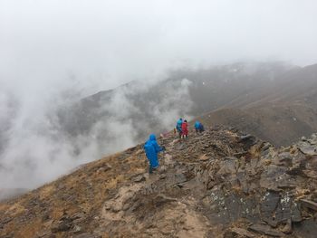 People walking on mountain against mountains