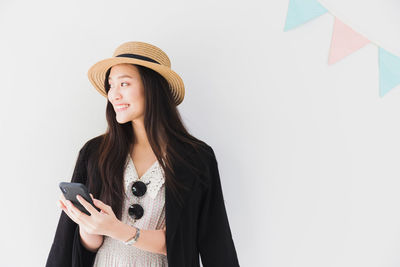 Woman wearing hat standing against white background