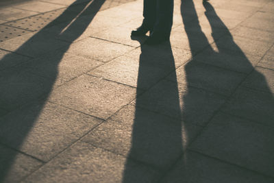 Low section of man with shadow standing on footpath