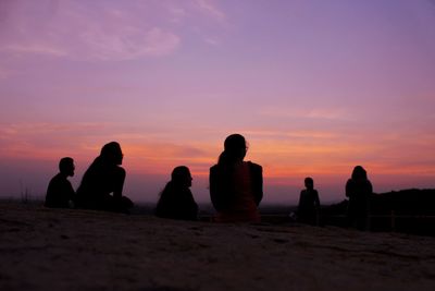 Silhouette people on beach against sky during sunset