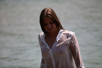 Portrait of a beautiful young woman standing against sea