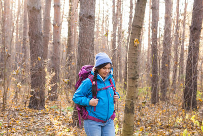 Woman wearing hat in forest during winter