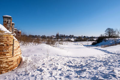 Snow covered field against clear blue sky during winter