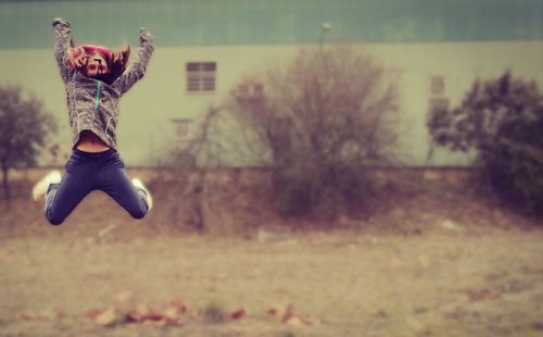 Full length of woman jumping against building