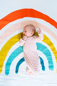 View from above of a newborn baby on a rainbow colored blanket