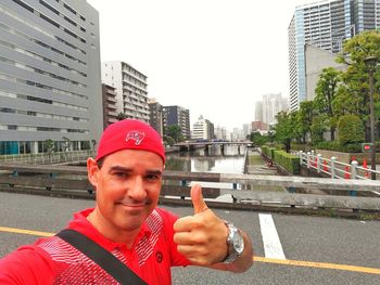 Portrait of smiling man standing on road in city