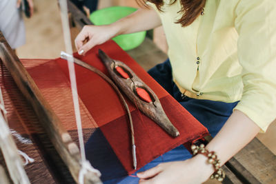 Midsection of woman working on loom in factory