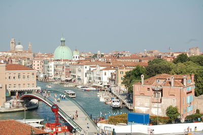 Canal passing through city against clear sky