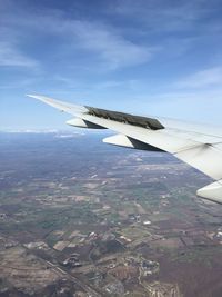 Aerial view of airplane wing over landscape against sky