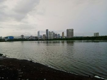 Buildings by river against sky in city