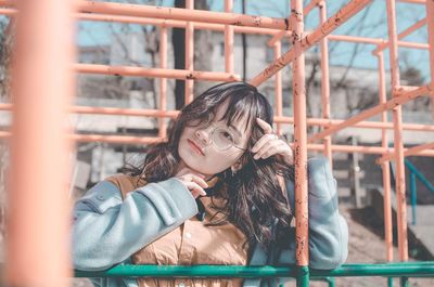 Portrait of young woman standing against railing