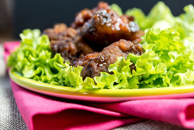 Close-up of roasted chicken with lettuce in plate on table