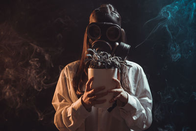 Midsection of person holding mask against black background