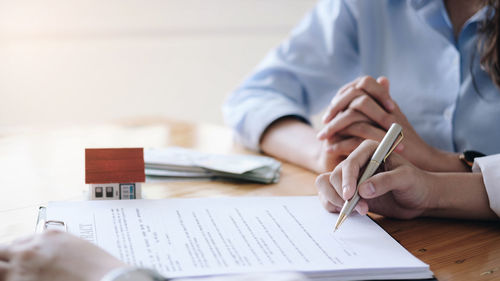 Midsection of man reading book on table