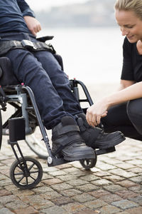 Female caretaker putting on disabled man's shoes outdoors