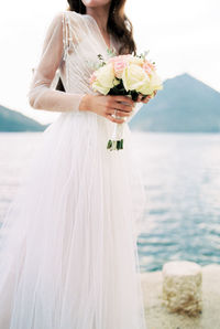 Midsection of bride holding bouquet