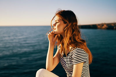 Beautiful young woman in sea against sky