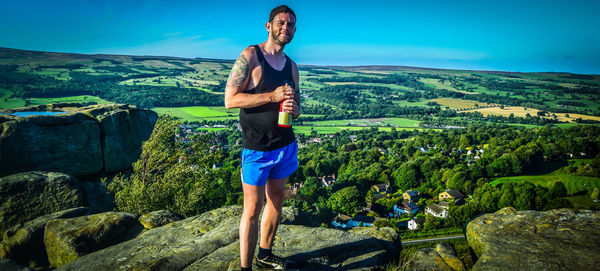 Man standing on cliff against green landscape