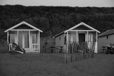 Hut on beach by house against sky