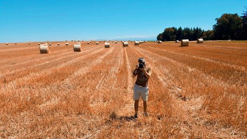 Photographer standing on field against sky