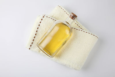 High angle view of towel with oil in bottle over white background