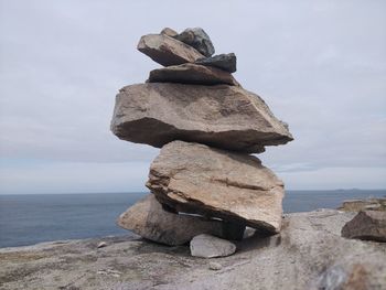 Stack of rocks by sea against sky