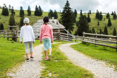 Rear view of women walking on grassland