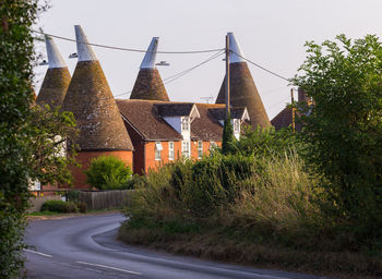 Road by trees and buildings against sky