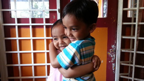 Happy siblings hugging at home