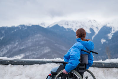 Caucasian woman in a wheelchair travels in the mountains in winter