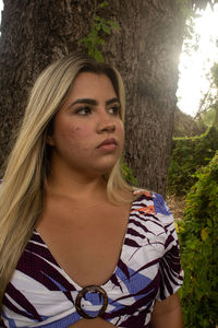 Portrait of young woman with tree trunk