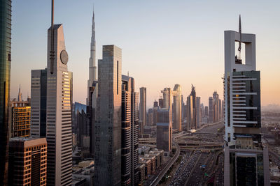 Modern buildings in city against sky during sunset