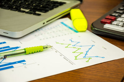 Close-up of graph paper with laptop and pen on desk