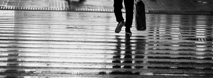 Low section of woman walking on wet shore