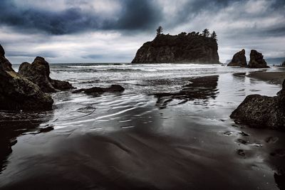 Rock formation on beach against sky