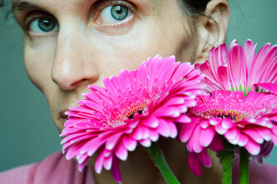 Close-up portrait of mature woman holding pink flowers