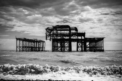 Pier on sea against cloudy sky