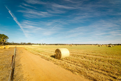 Hay bales on field against sky