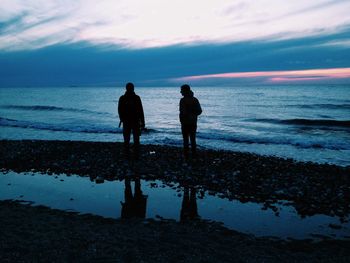 Silhouette people on beach against sky during sunset