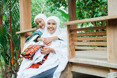 Portrait of mother and daughter embracing outside home