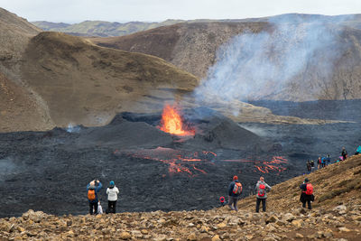 Group of people on mountain, watching eruption in iceland 