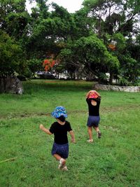 Rear view of mother and girl running on grass